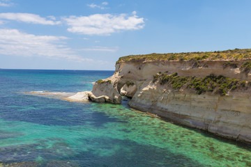 natural stone arch over the beautiful azure turquoise Mediterranean sea and white chalk limestone cliffs of St Thomas Bay, walking, trekking, hiking along the Munxar Path, Marsaskala, Malta