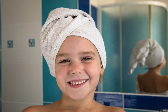 Little girl in bathroom with towel on a head.