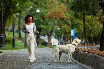 Pretty young lady walking with dog in park in the morning