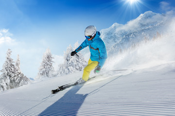 Young man skier running down the slope in Alpine mountains