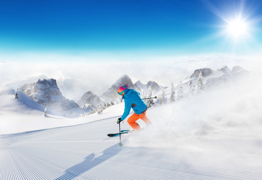 Young man skier running down the slope in Alpine mountains