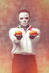 Human skeleton holding two pumpkins in his hands. the character at Halloween. Man holding a pumpkin...