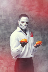 Male african american in the role of a zombie and skeleton. Man is holding two orange pumpkin Halloween holiday symbol. Portrait of an african man - festival, carnival, party, Halloween. Voodoo people