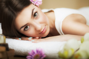 Obraz na płótnie Canvas Portrait of a beautiful girl in a spa. Gentle look. Flowers in hair. Aroma oil. Massage cabinet. The concept of health and beauty.
