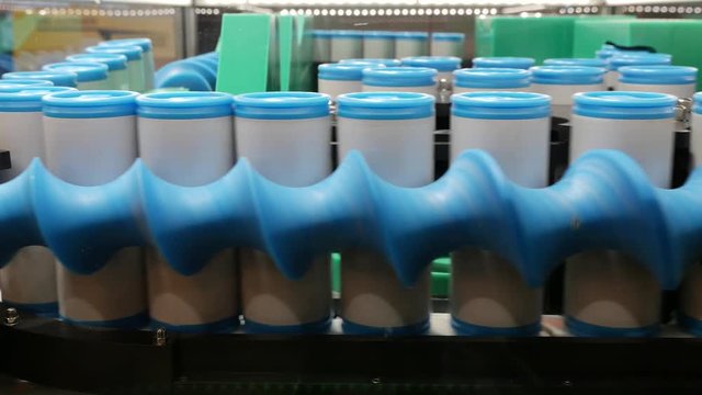 Blue and white plastic cans on an industrial conveyor belt in a factory &ndash; 4K