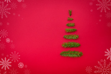 symbol Christmas tree from a fir branches on red background. Cop