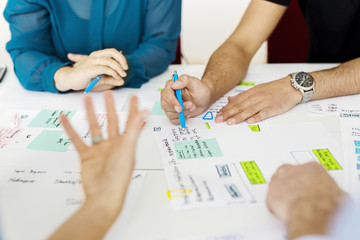 Colleagues sitting by conference table and brainstorming
