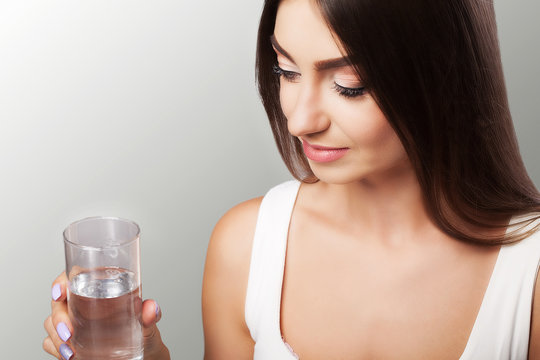Drink water from the glass. Healthy Lifestyle. Portrait of a happy young woman with a glass of fresh water. Health. Drinks Beauty. The concept of diet. Healthy Eating.
