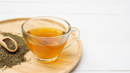 A cup of tea and a green tea leaf on a table.