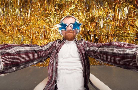 Selfie and party! Happy fun man. Girl with shaped stars glasses. Party club, fun to spend time. Young man holding camera and making selfie and smiling while standing against gold background
