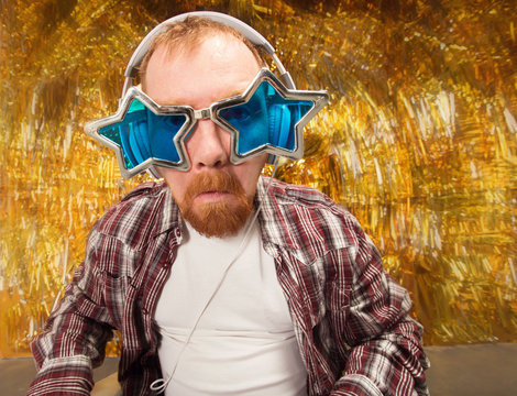 Selfie and party! Happy fun man. Girl with shaped stars glasses. Party club, fun to spend time. Young man holding camera and making selfie and smiling while standing against gold background - Powered by Adobe