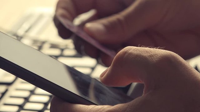 Electronic banking with mobile phone. Businessman holding smartphone and credit card, checking bank account balance, using online internet application on his electronics device