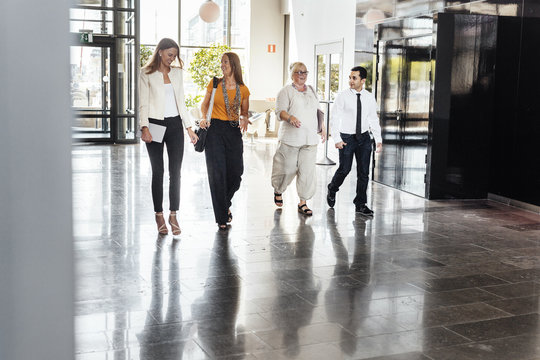 Four colleagues walking inside office building lobby