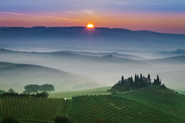 Naklejka premium Stunning foggy green fields at sunset in Tuscany