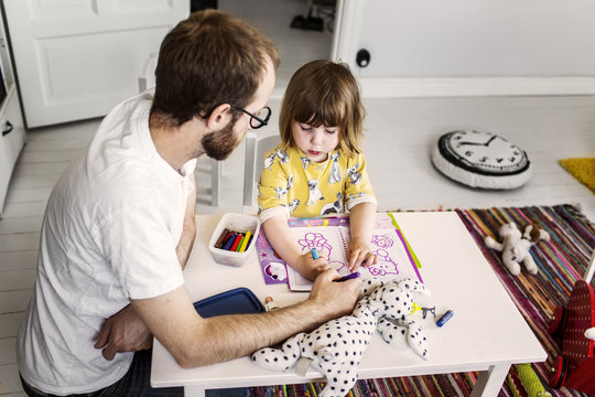 Father and daughter drawing in coloring book