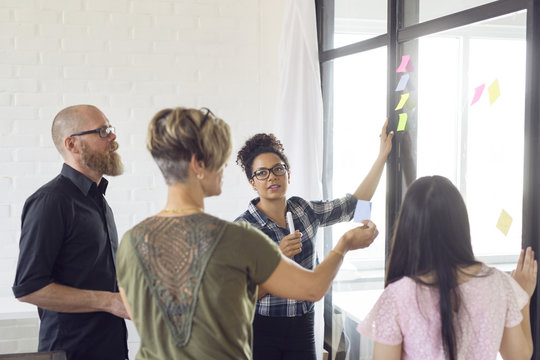 Office workers looking at glass wall with post-it notes