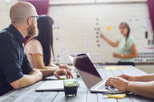 Coworkers looking at colleague pointing at whiteboard
