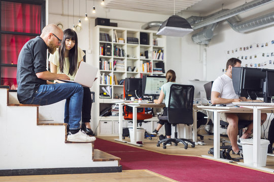 Coworkers using computers at office