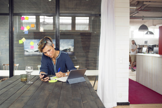 Woman writing in notebook at wooden table