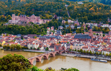 View on Heidelberg in autumn with red foliage including Carl Theodor Old Bridge, Neckar river, Church of the Holy Spirit, Germany