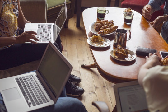 People sitting by coffee table with laptops or smart phones
