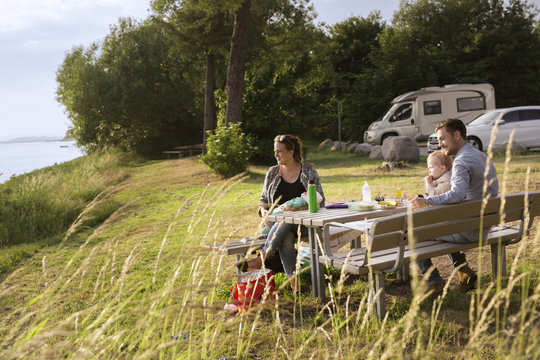 Parents with sons (18-23, 0-1 months) sitting by picnic table