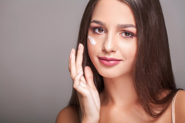 Beauty Skin Care. Beautiful Happy Woman Applying Cosmetic Cream On Clean Face. Closeup Portrait Of Healthy Smiling Female Model With Natural Makeup, Fresh Soft Pure Skin Applying Moisturizing Lotion