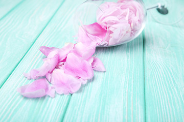 Peony petals in glass on mint wooden table