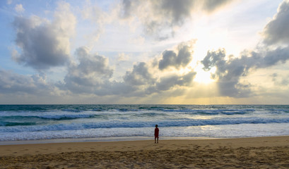 child by the sea at sunset looks at the waves