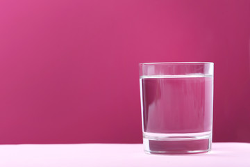Glass with water on pink background