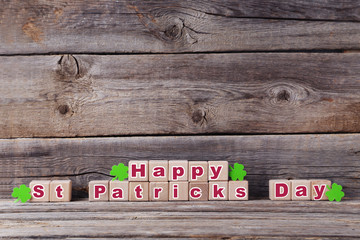 Wooden toy cubes and green paper clover leafs on grey table