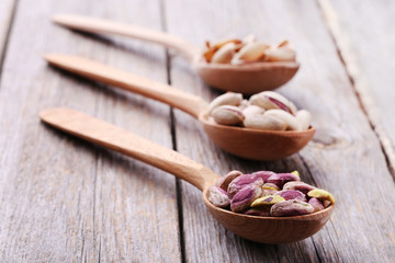 Pistachios in spoons on grey wooden table