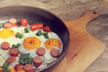  hot dish in a frying pan/ fried eggs with sausages and greens on a wooden stand 