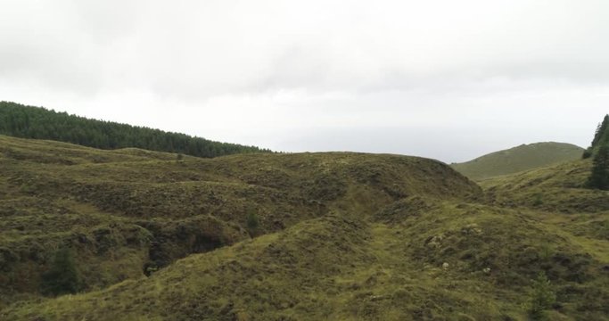 Aerial drone fly over lookalike hobbit green hills with misty clouds 
