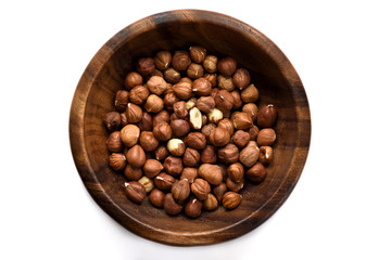 Hazelnuts in a wood bowl and loose isolated over white background.