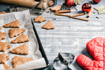 Christmas gingerbread chocolate cookies on baking pan. Fresh baked star and fir-tree shaped biscuits on wooden background
