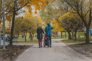 Fototapeta premium love, parenthood, family, season and people concept - smiling couple with baby pram in autumn park