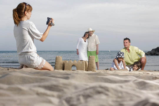 Mother taking video of family on beach