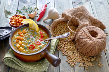 Spicy lentil soup with chili, garlic and onion on wooden table