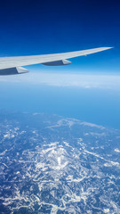 Obraz premium Aerial view from airplane window over Japan with airplane's wing,mountains covered snow and blue sky background.