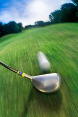 Golf club hitting ball on golf course © Image Source RF