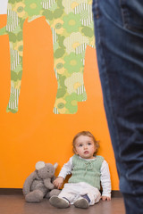 Young girl on floor,  mothers legs aside