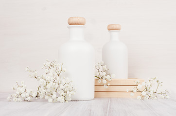 Fototapeta na wymiar Spa template of blank white cosmetics bottles with small flowers on white wood board, copy space. Soft elegant home decor for advertising, designers, branding identity, cover..
