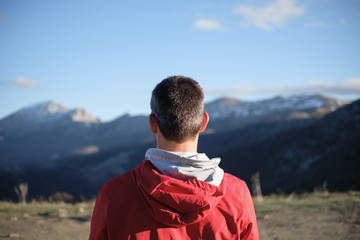 Back view of athlete taking a rest for watching the mountain during outdoor late winter training.