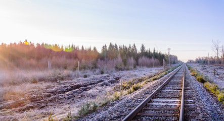 Fototapeta premium Frosty morning sunrise at the traintracks leading into the unknown distance