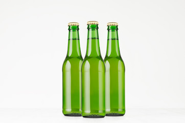 Group green longneck beer bottles 330ml, mock up. Template for advertising, design, branding identity on white wood table.