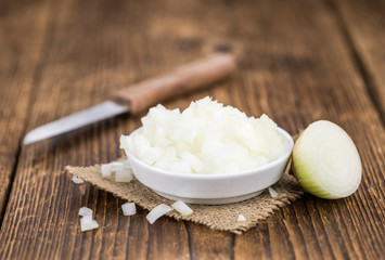 White Onions (dices) on wooden background; selective focus