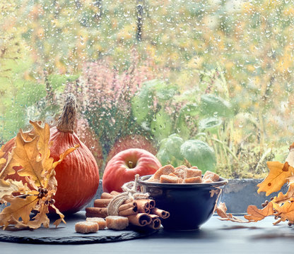 Pumpkins, cinnamon, sugar and leaves by the window on a rainy day