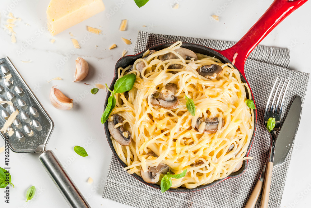 Wall mural Creamy mushroom pasta with cheese and basil, in portioned frying pan, on white marble table, copy space top view