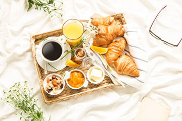 Continental breakfast on white bed sheets - flat lay